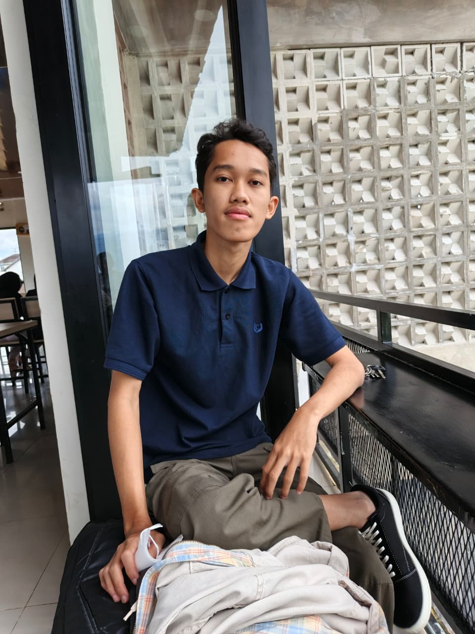 Pandu sitting outdoors in a blue shirt